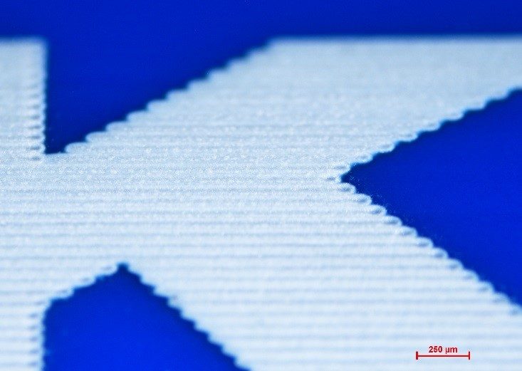 a blue nylon tube marked with high-contrast alphanumeric characters using the ORIGAMI XPS femtosecond laser for precise polymer tube identification.