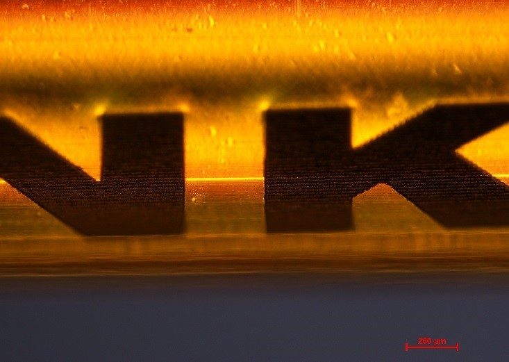 close-up of yellow polyimide tube marked with high-contrast identifiers using ORIGAMI XPS femtosecond laser for medical and industrial applications.